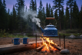 Basecamp enamel kettle and mugs around a campfire at dusk